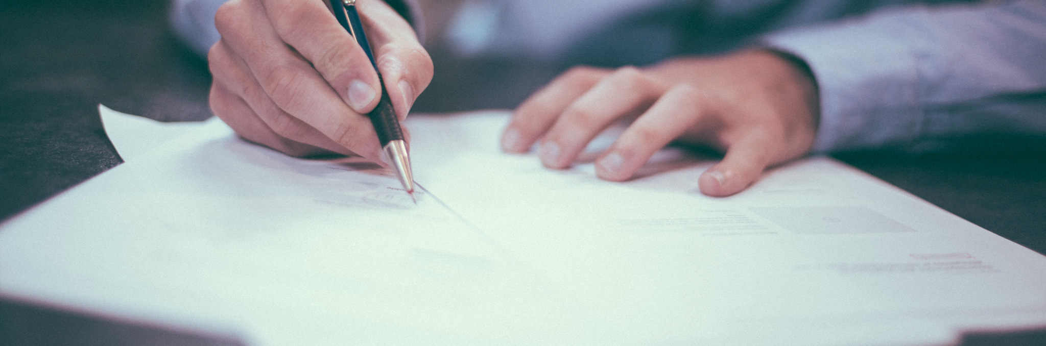 Person signing documents. Photo by Helloquence on Unsplash