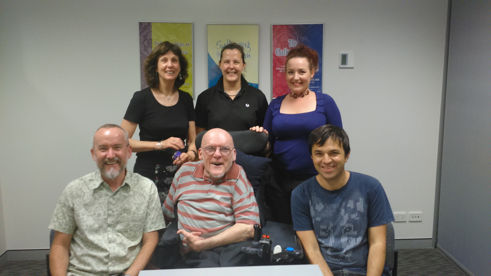 6 people smiling at the camera.  One of them is in a wheelchair