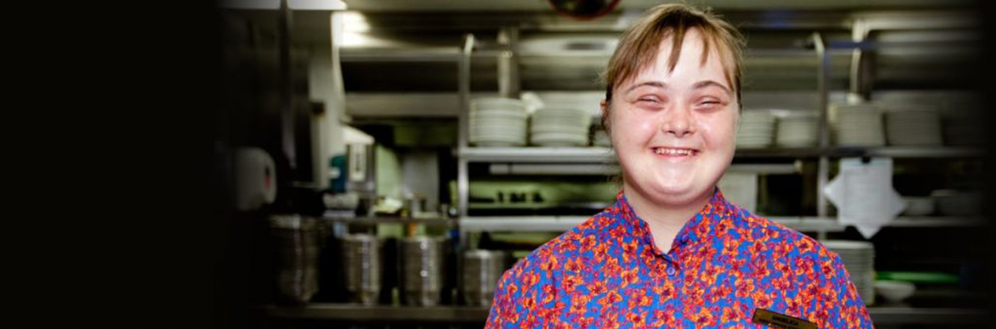 Young woman with Downs syndrome smiling in commercial kitchen