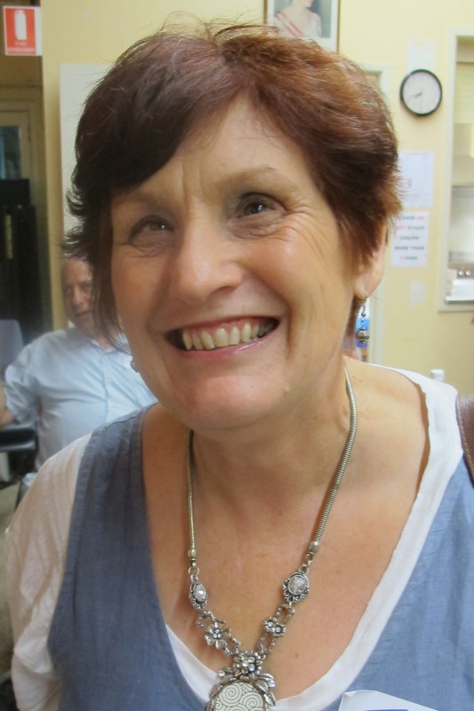 Josey wearing a blue and white top with an antique necklace, smiling broadly