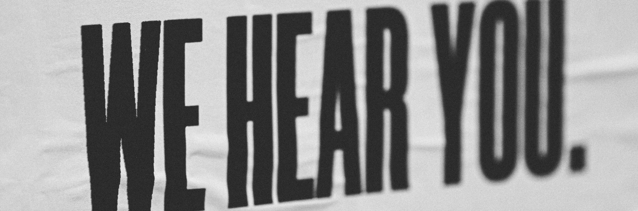 A sign in black letters saying We Hear You