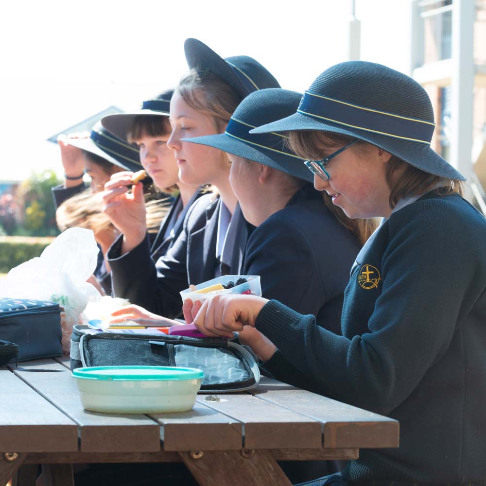 Row of girls in school uniform eating lunch