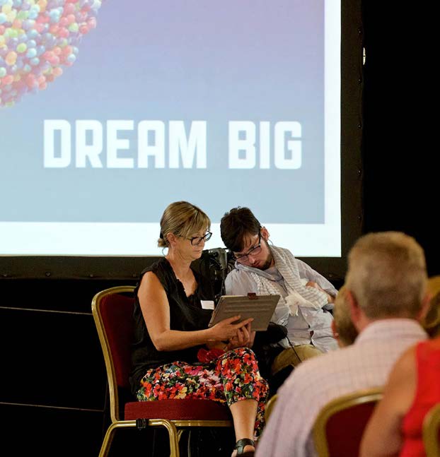 Presentation to a room with a screen in the background that says Dream Big