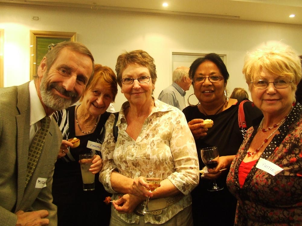 Five people - one man and four older women - standing together with name tags and holding wine glasses.