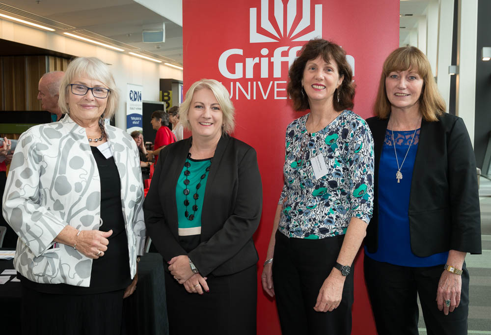 4 women, including a government minister and cru's director, standing together at a conference in front of a banner that has the Griffith University logo on it