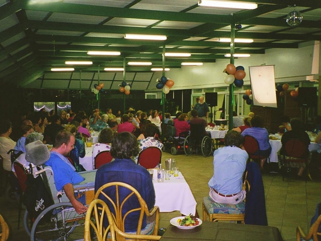 People, some in wheelchairs, gathered in a hall for a cru event