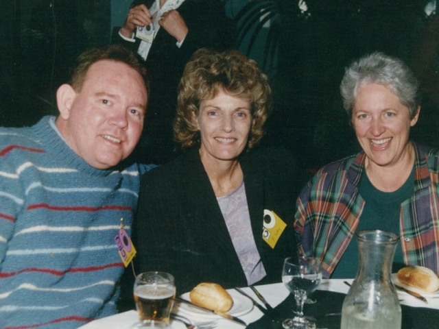 A man and two women sitting together at a dinner table at a conference