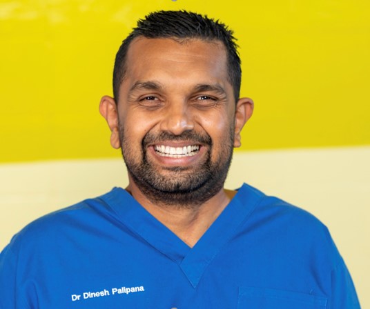 Dr Dinesh Palipana smiling warmly in his medical scrubs