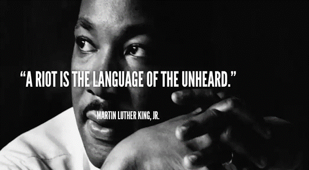 A black and white photo of Dr Martin Luther King with a quote from him in text over the image. A riot is the Language of the unheard.