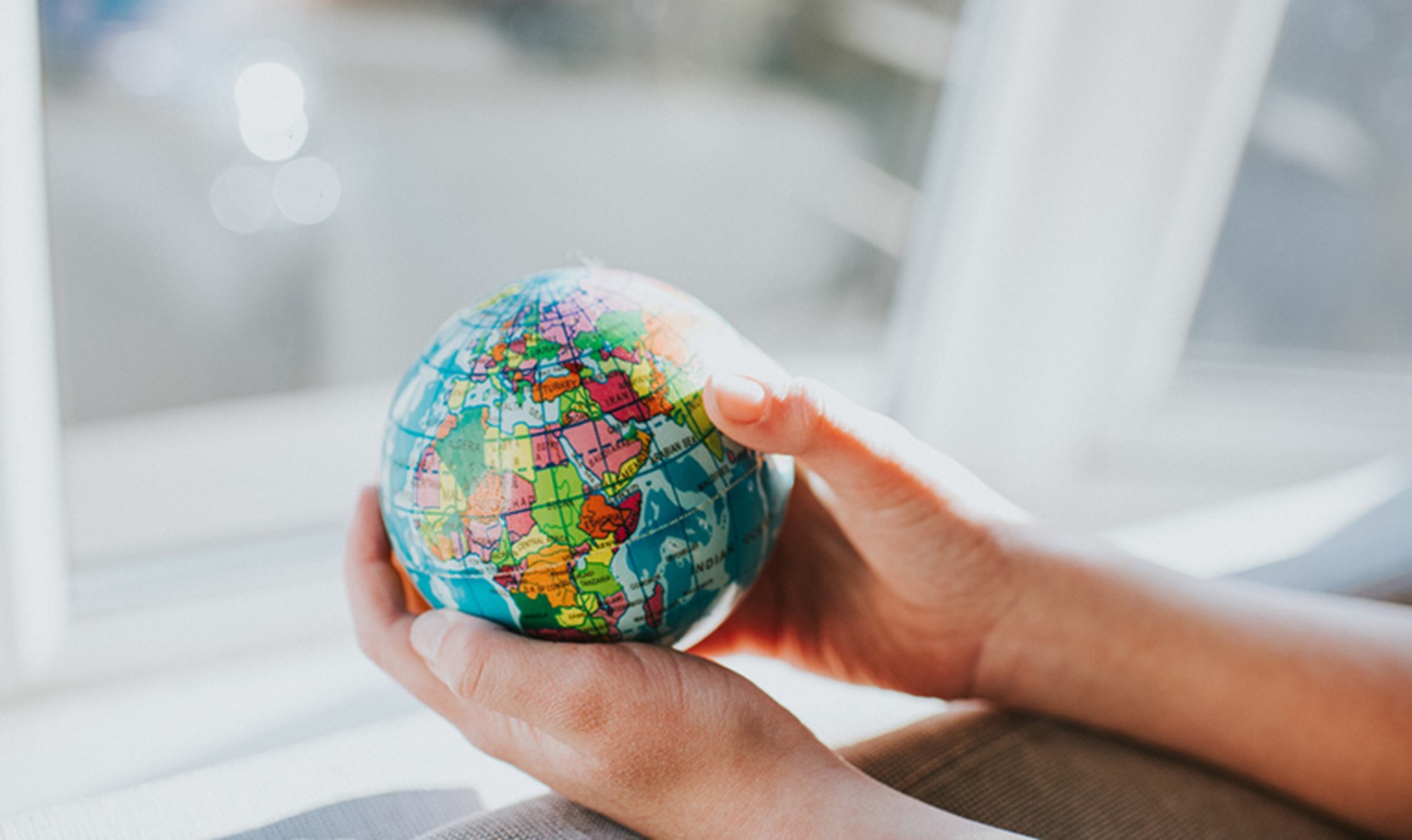 Two hands holding a small globe of the world