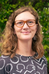 Meegan with long hair and glasses, smiling