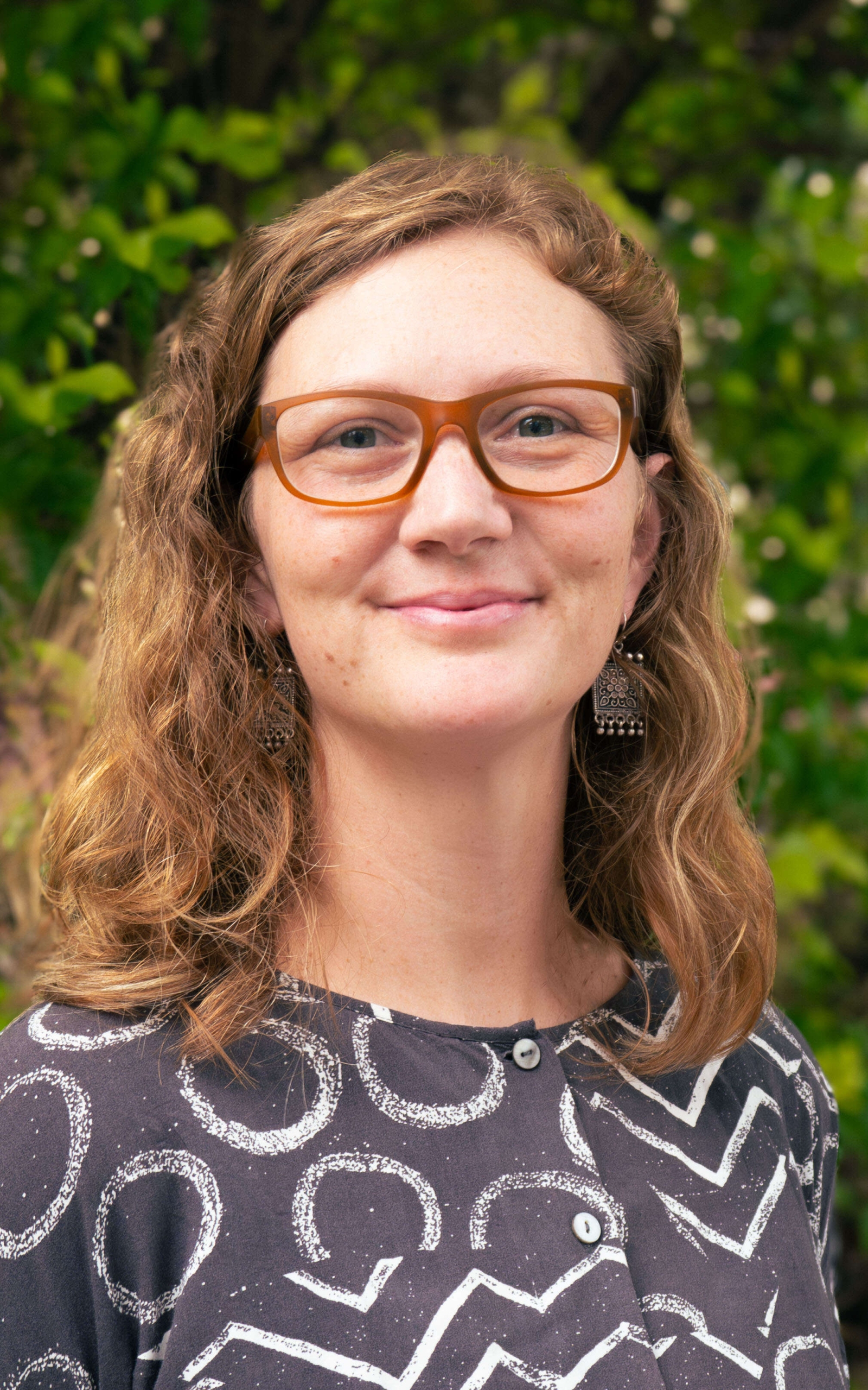 Meegan with long hair and glasses, smiling