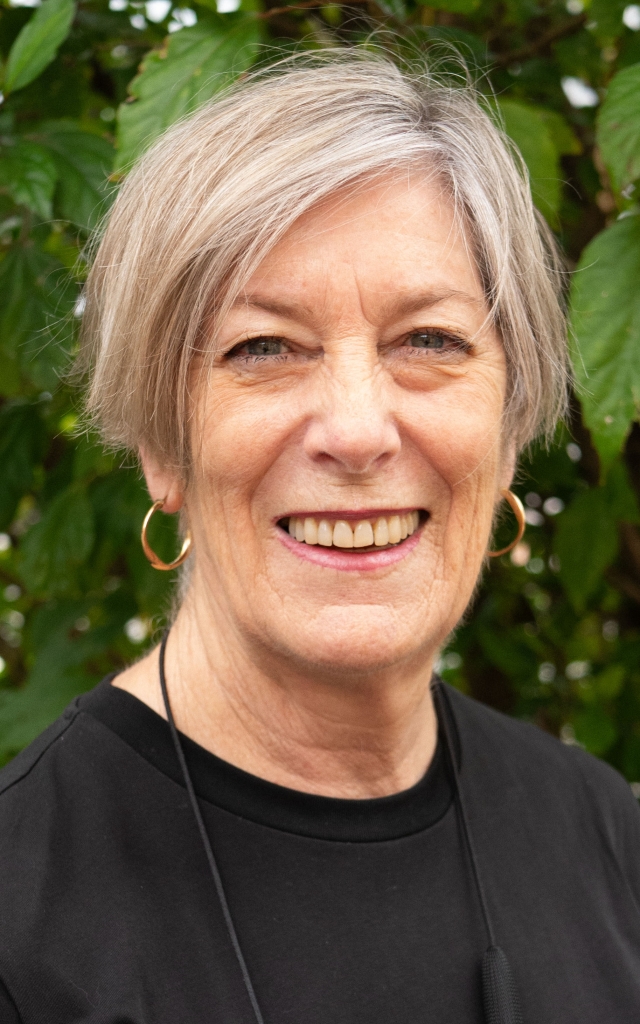 Anne Leahy with short hair wearing a black shirt smiling.