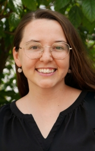Kyla Ranger wearing glasses and a black shirt smiling.